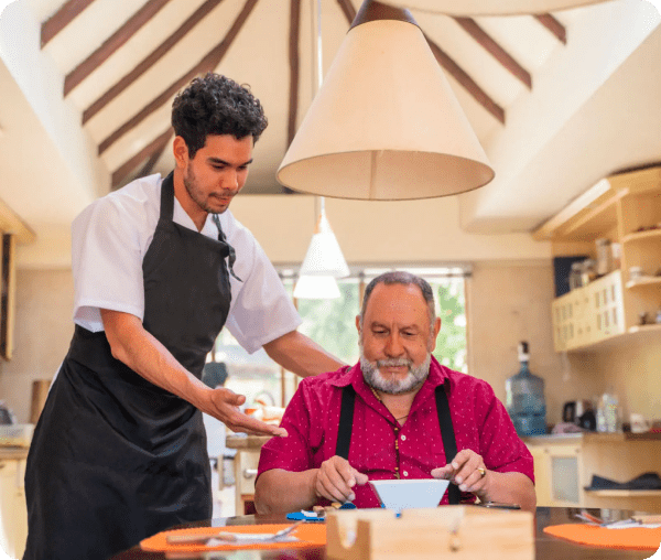 A waiter serves food to a seated elderly man in a cozy restaurant.